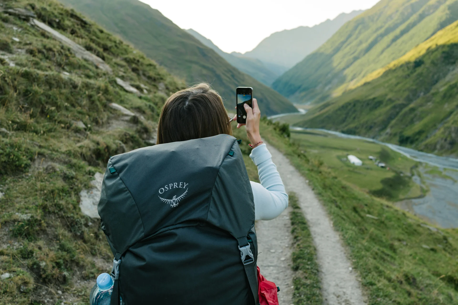 A traveler photographing a green mountain valley